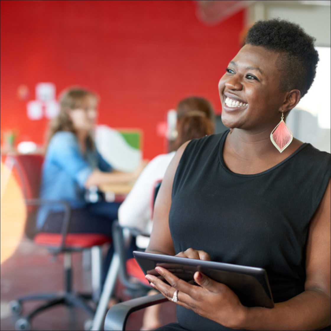 woman in an office smiles while holding a tablet